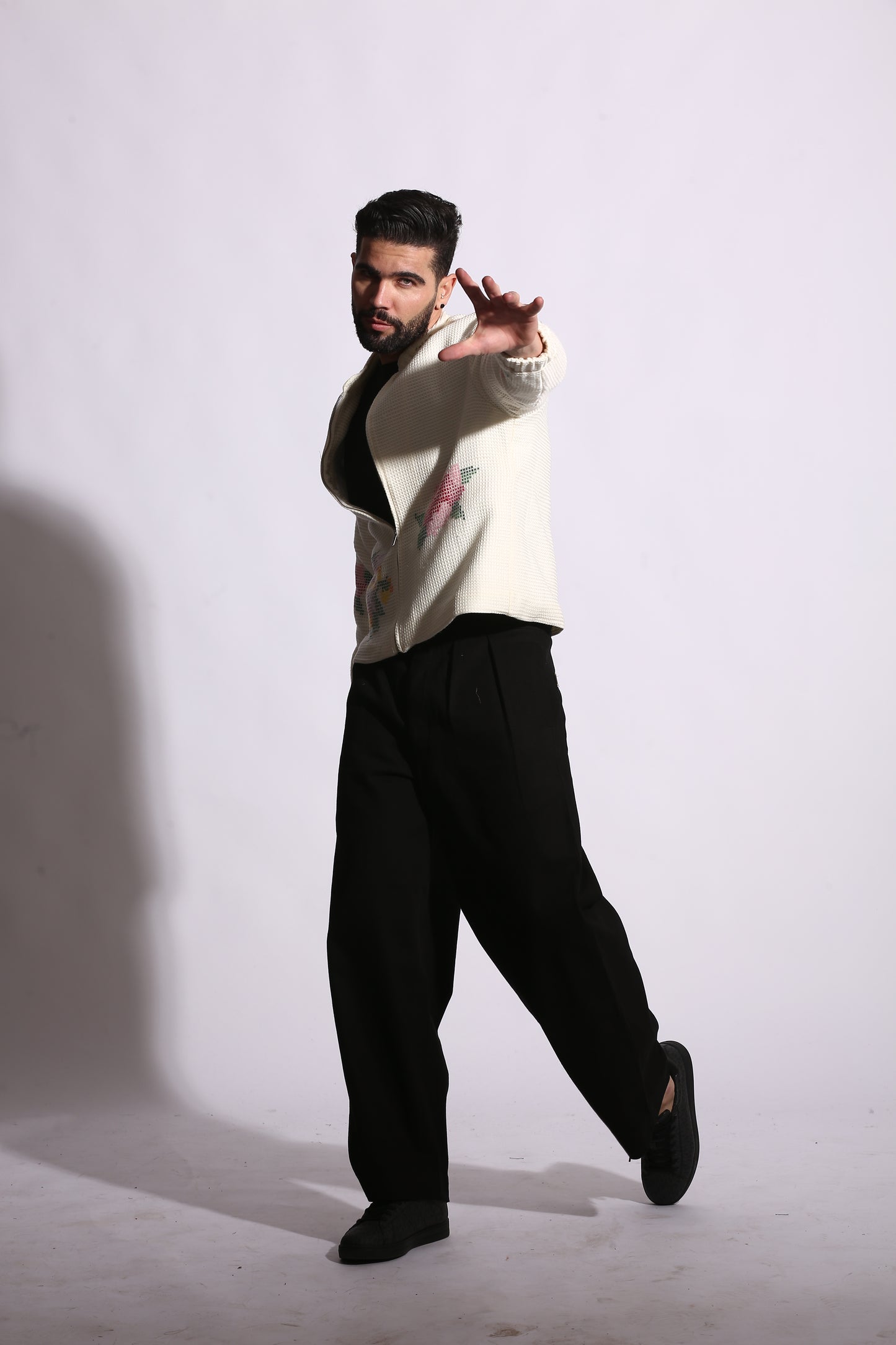 Person wearing a white shirt with a colorful design on a plain background