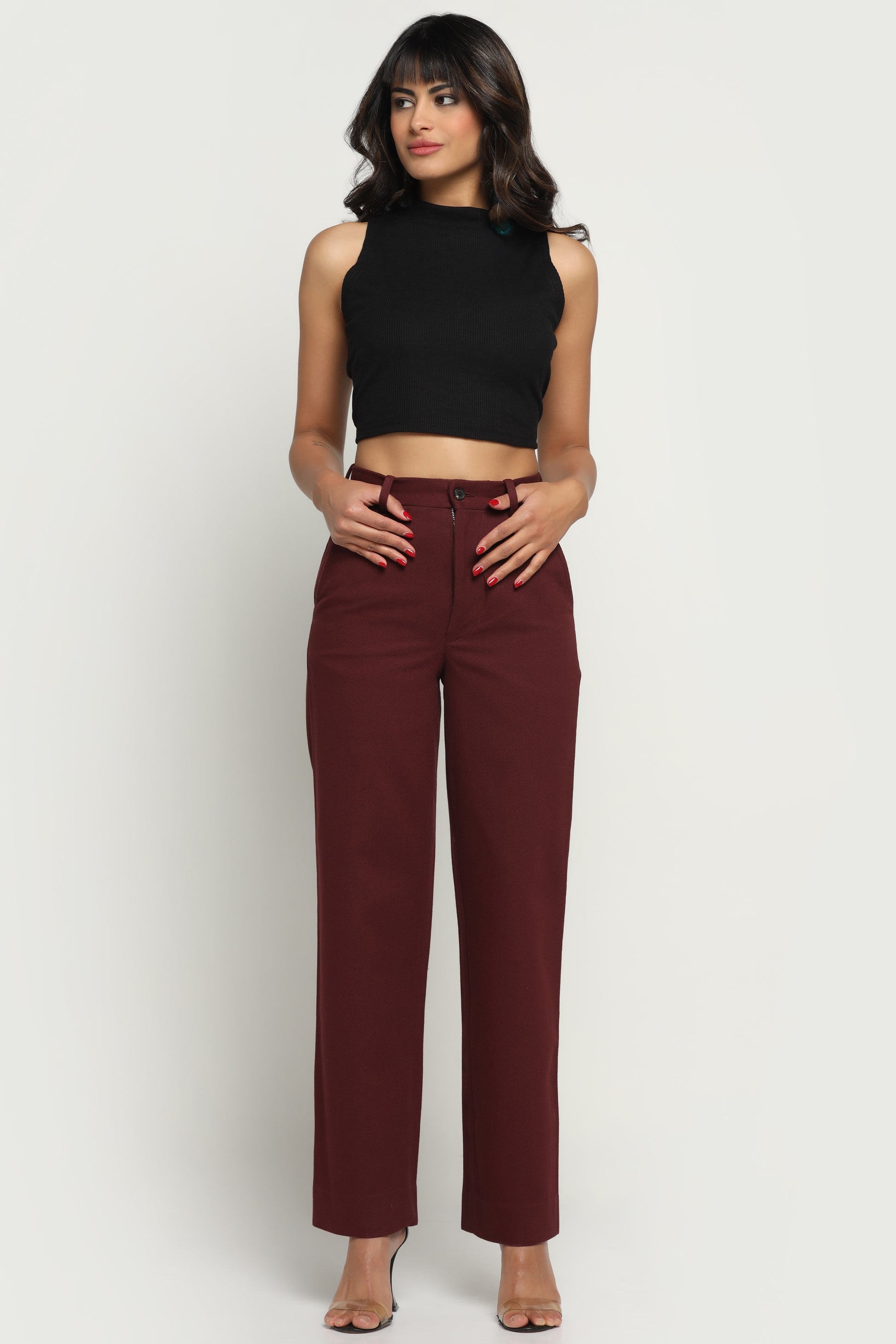 Woman wearing a black sleeveless top and maroon pants on a white background