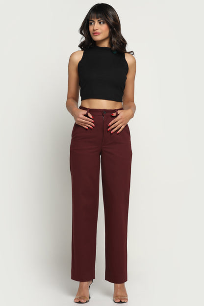 Woman wearing a black sleeveless top and maroon pants on a white background