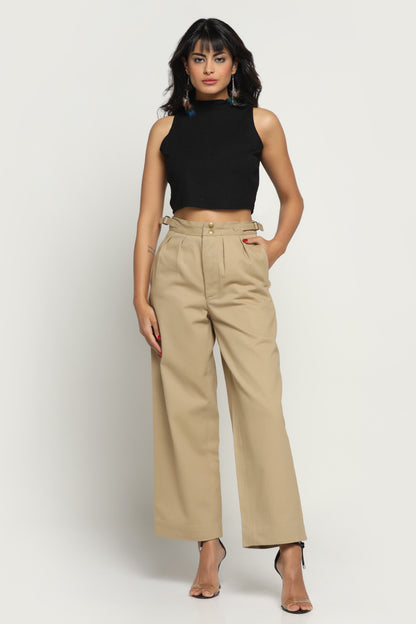 Woman wearing a black sleeveless top and beige high-waisted pants on a white background