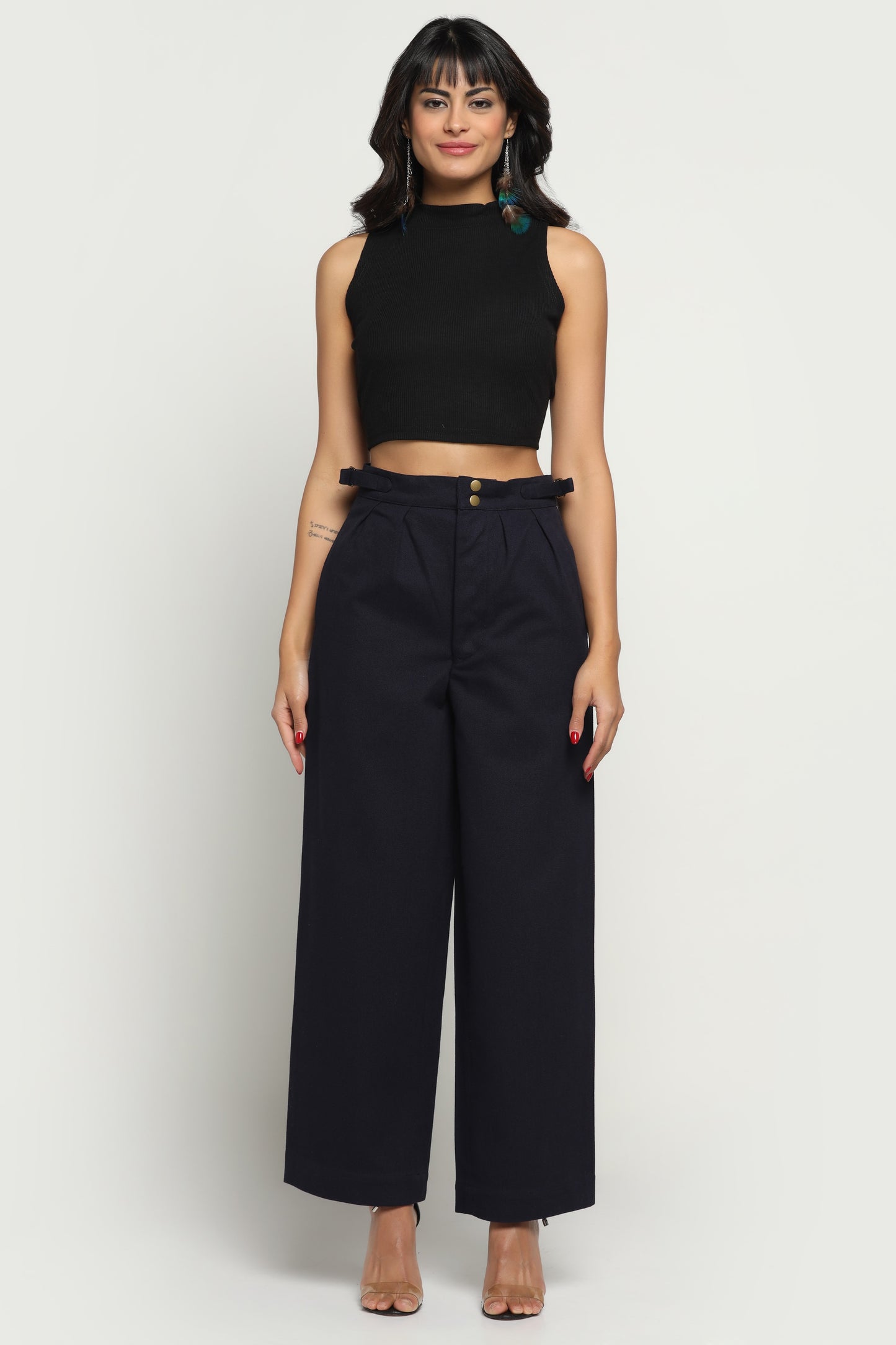 Woman wearing a black sleeveless top and wide-leg pants on a white background