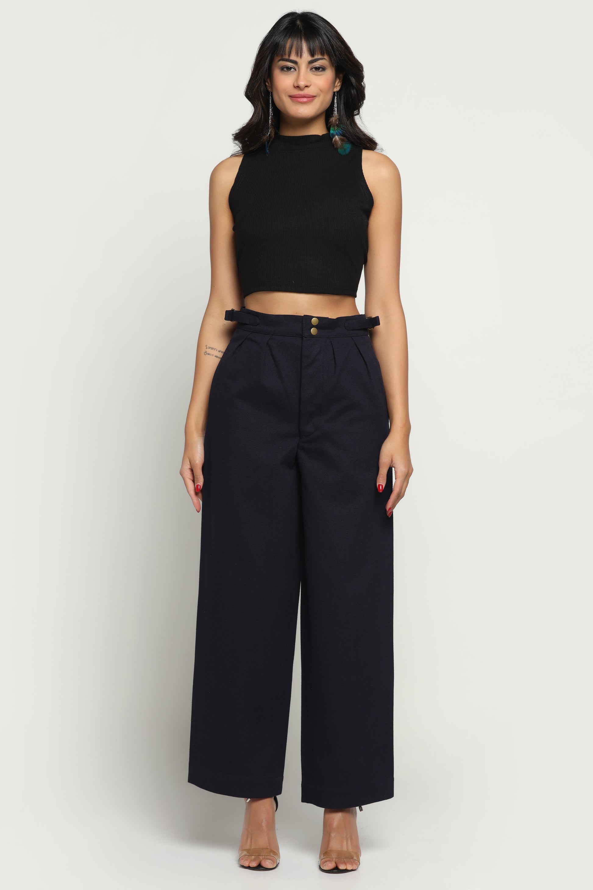 Woman wearing a black sleeveless top and wide-leg pants on a white background
