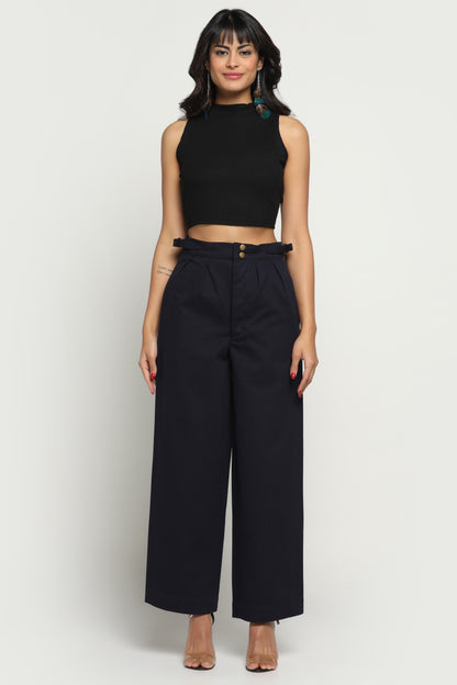 Woman wearing a black sleeveless top and wide-leg pants on a white background