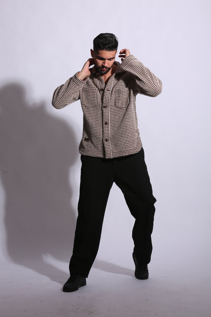 Person wearing a patterned jacket and black pants on a white background
