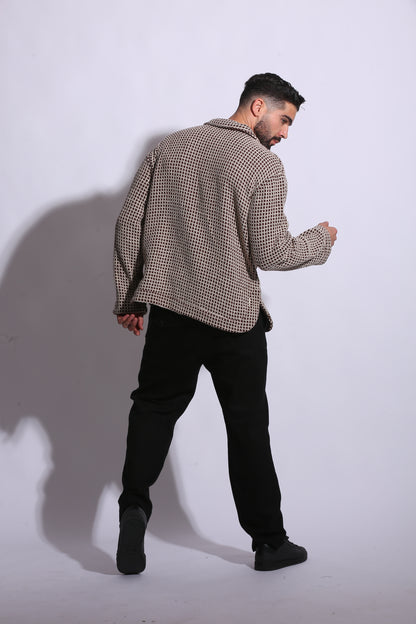 Person wearing a patterned coat and dark pants on a white background