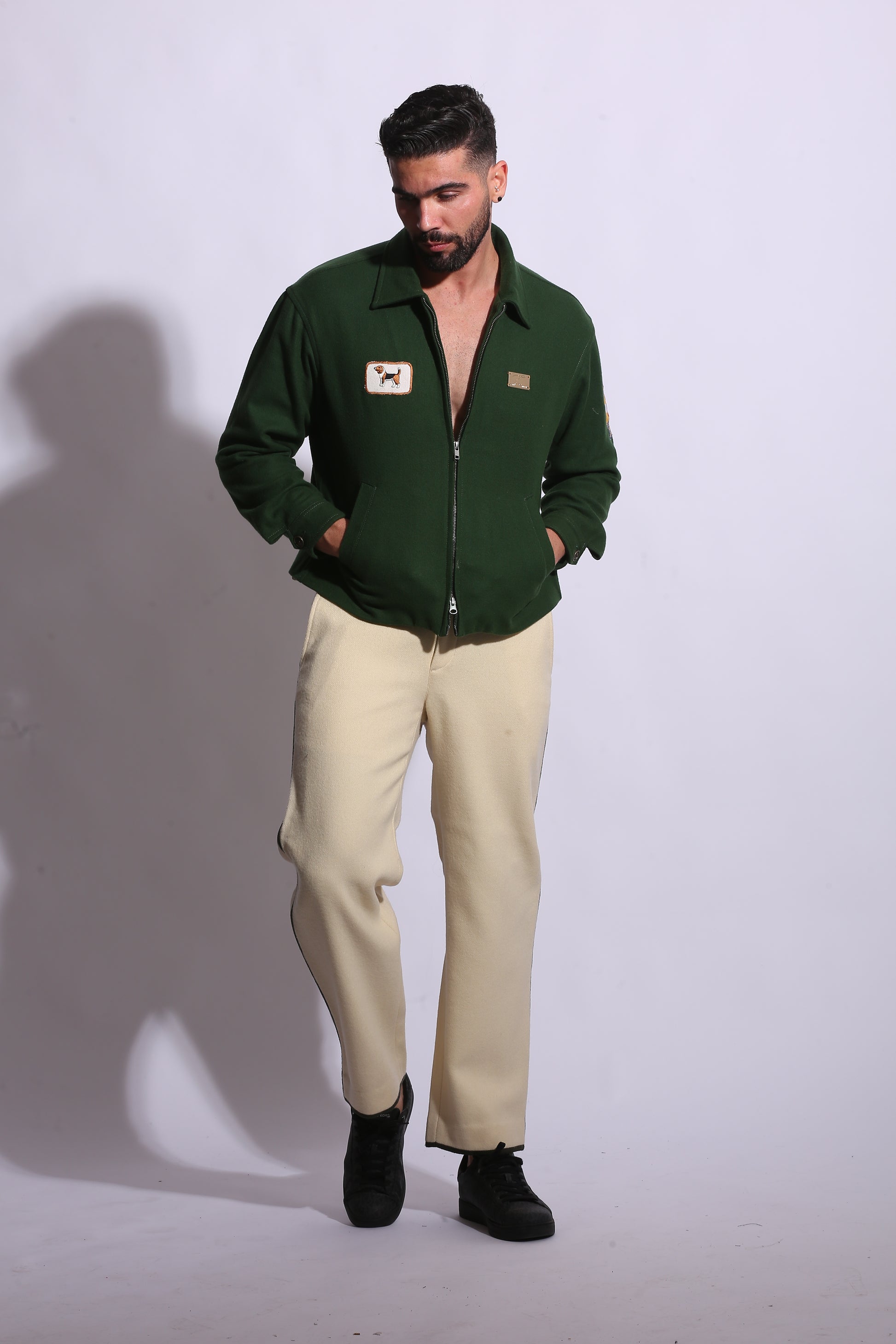 Person wearing a green jacket and beige pants on a white background