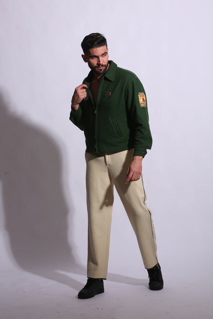 Person wearing a green jacket and beige pants on a white background