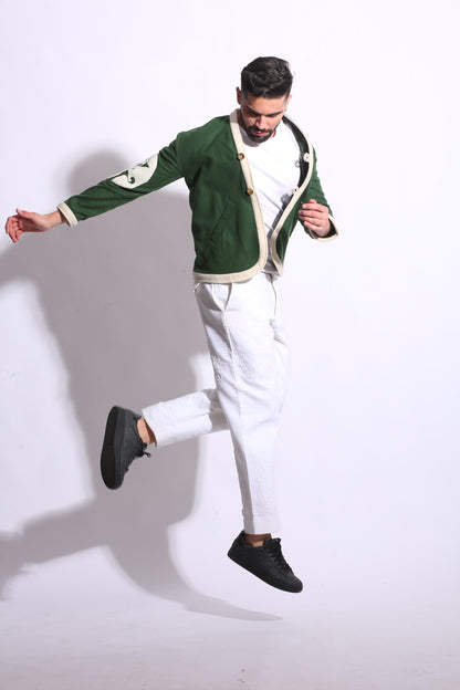 Person wearing a green jacket and white pants on a white background