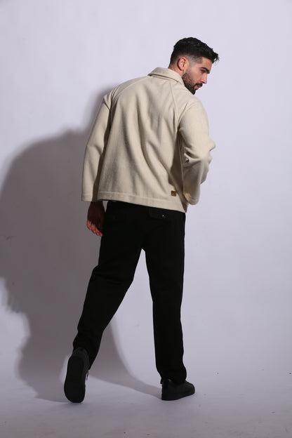 Person wearing a beige coat and black pants on a white background