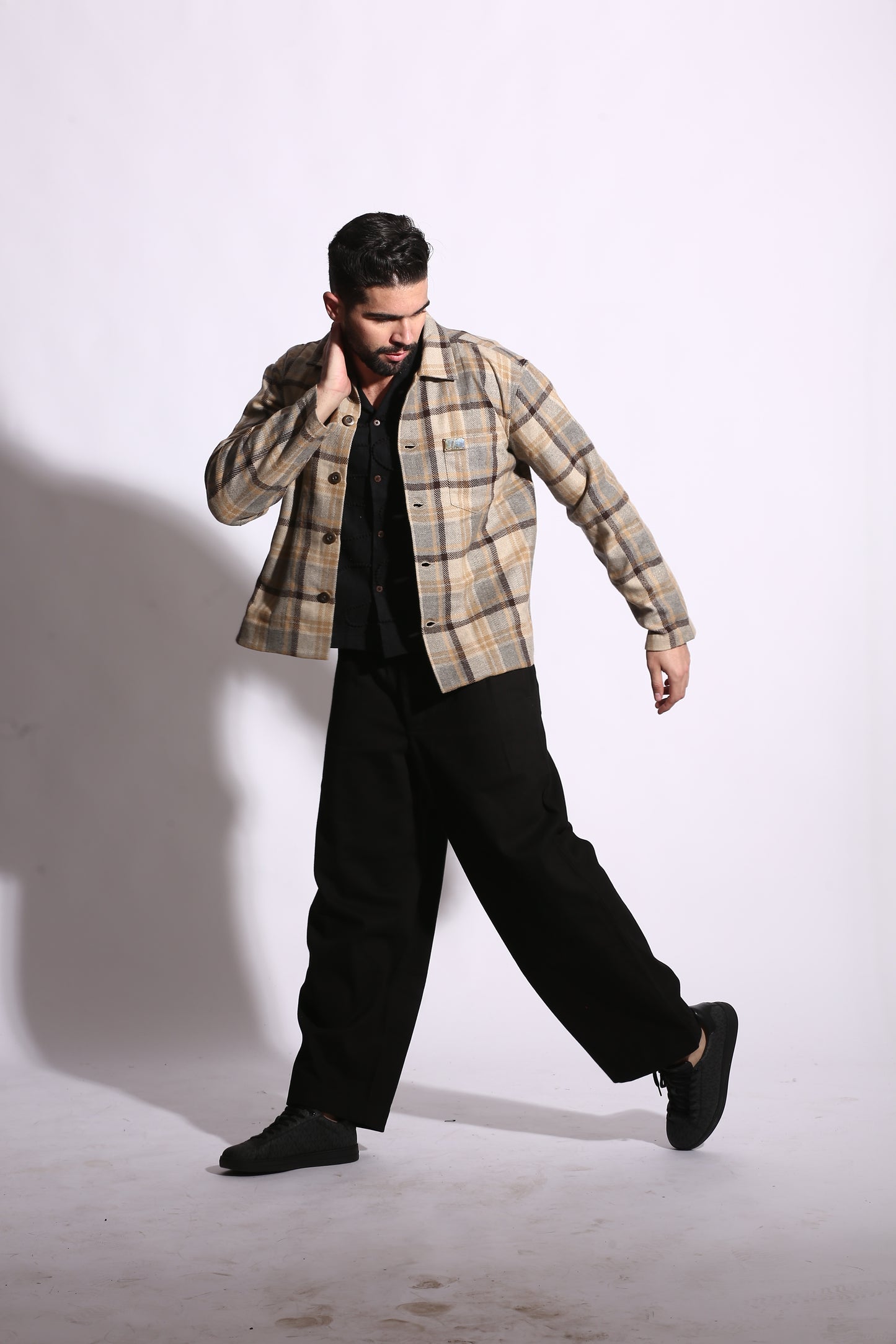 Person wearing a plaid shirt and black pants on a white background