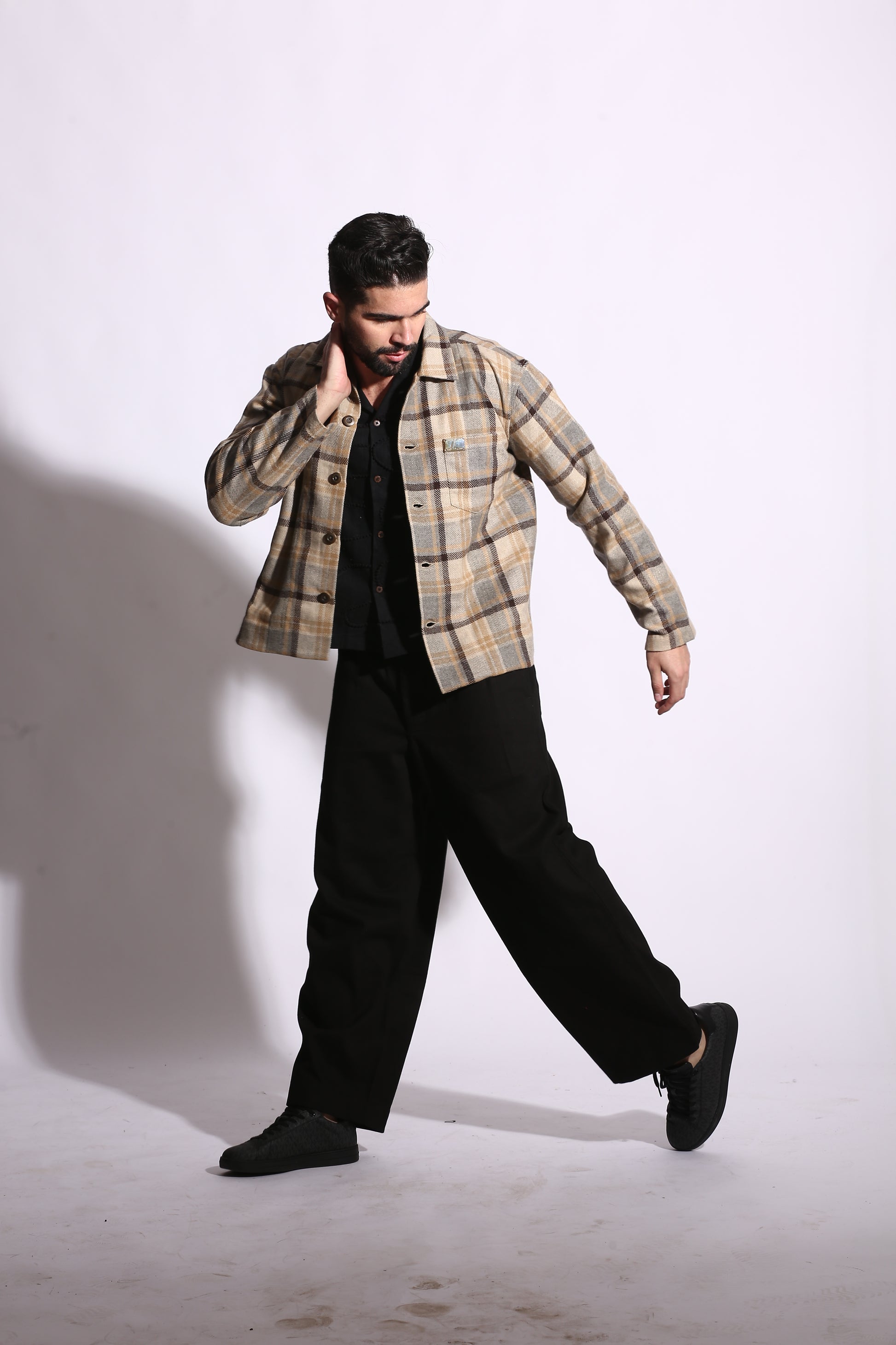 Person wearing a plaid shirt and black pants on a white background