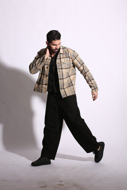Person wearing a plaid shirt and black pants on a white background