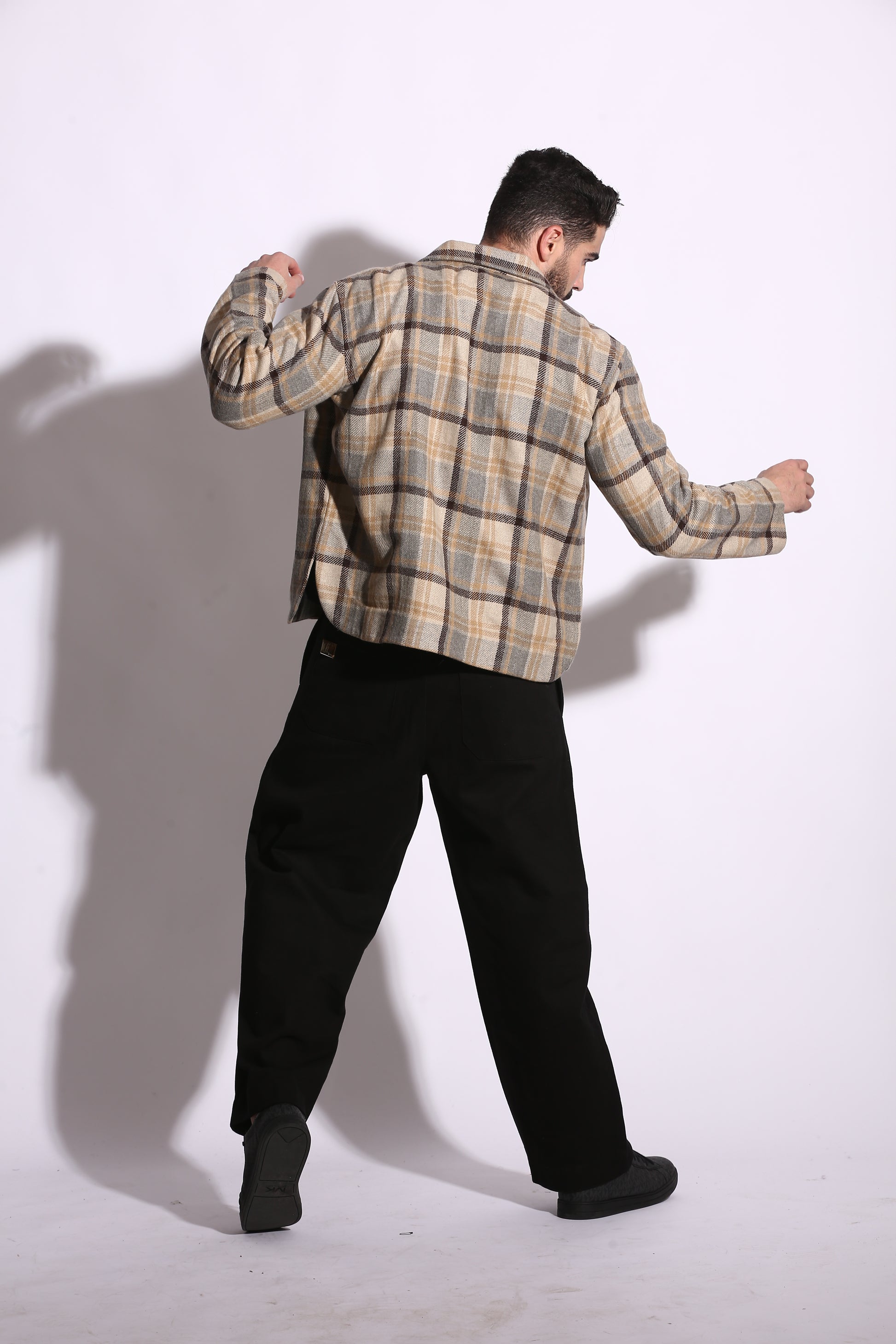 Person wearing a plaid shirt and black pants on a white background