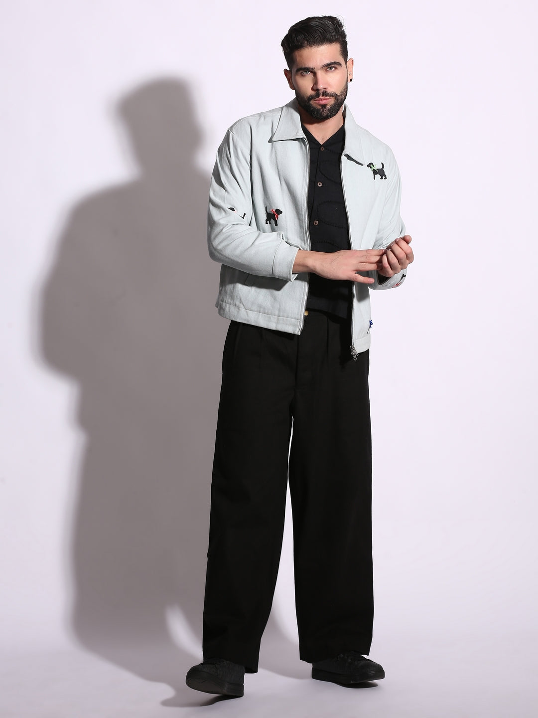 Man wearing a light gray jacket and black pants on a white background