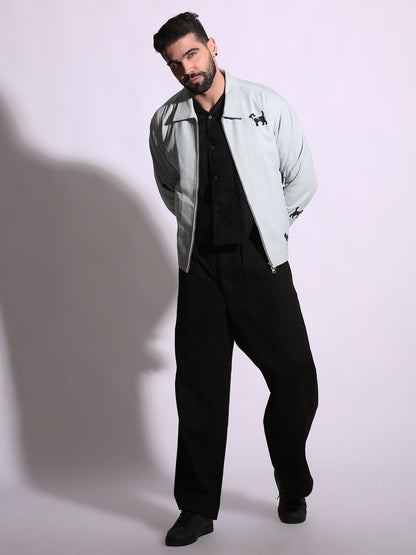 Man wearing a light gray jacket over a black shirt and pants on a white background