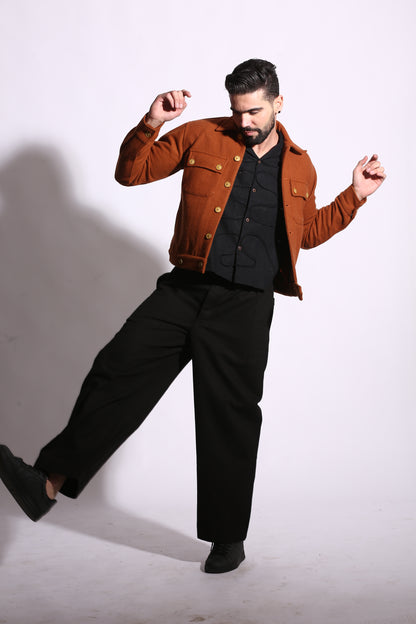 Man in a brown jacket and black pants posing against a white background
