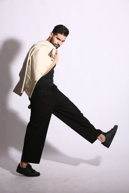 Person in black pants and gold jacket posing on a white background