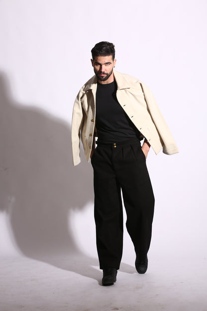 Man wearing a beige trench coat over a black outfit on a white background