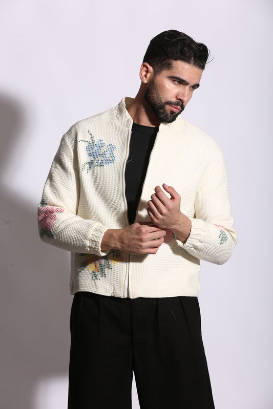 Person wearing a cream-colored sweater with floral patterns on a white background