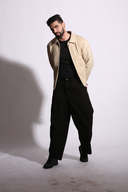 Man wearing a beige jacket and black pants on a white background