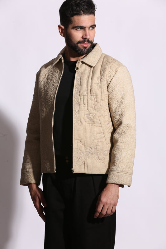 Man wearing a beige embroidered jacket on a white background