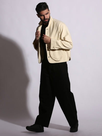 Man wearing a beige jacket and black pants against a white background