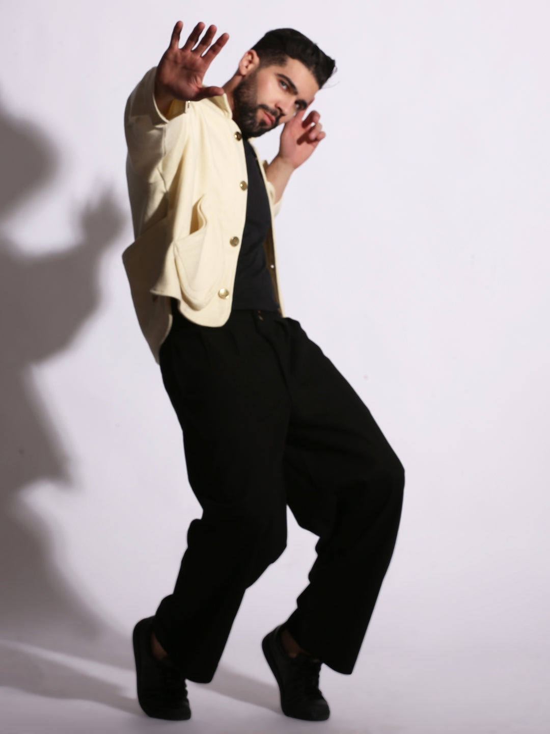 Man in a white shirt and black pants posing against a white background