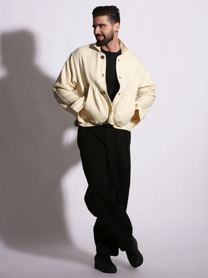 Man wearing a beige jacket over a black shirt and pants on a white background