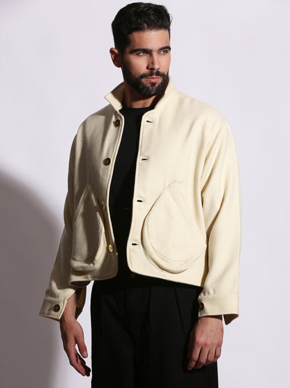 Man wearing a cream-colored jacket over a black shirt on a white background
