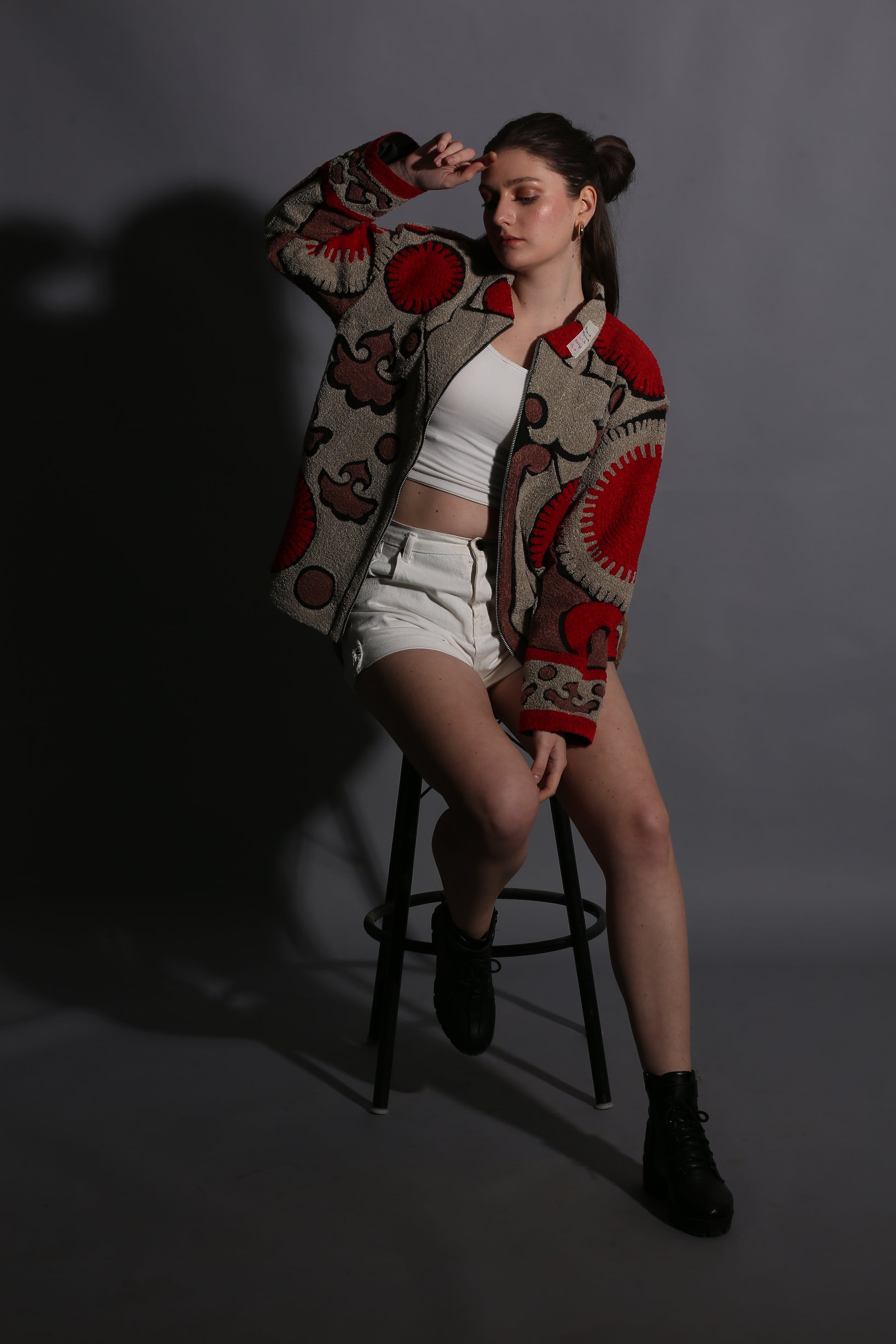 Person wearing a patterned scarf sitting on a chair against a dark background
