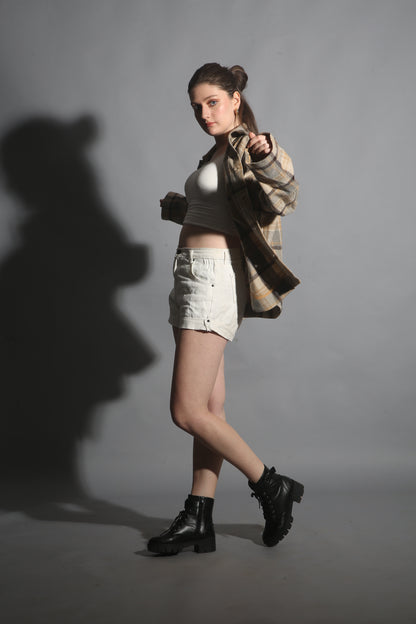 Person wearing a coat and boots with a dramatic shadow on a gray background