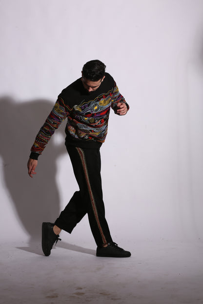 Person wearing a colorful sweater and black pants on a white background